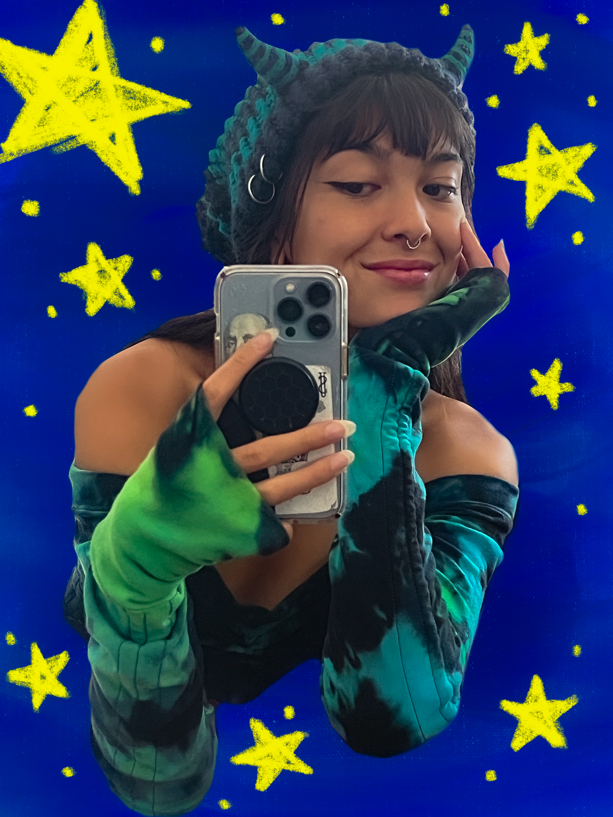 Mirror selfie in a teal and black tie-dye set with fingerless gloves and a horned, dragon-scale hood, over a starry blue backdrop